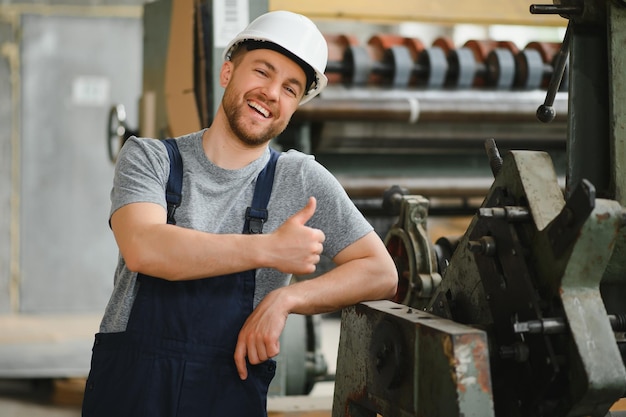 Empleado sonriente y feliz Trabajador industrial en el interior de la fábrica Técnico joven con casco blanco
