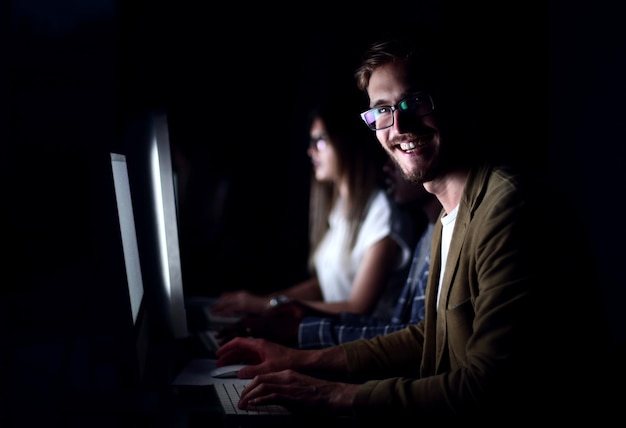 Empleado sonriente que trabaja en la oficina por la nochefoto con espacio para copiar