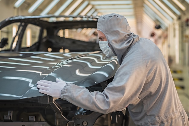 Un empleado del taller de pintura de una fábrica de automóviles comprueba la calidad de la superficie pintada.