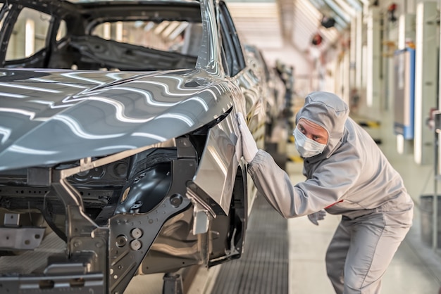 Un empleado del taller de pintura de una fábrica de automóviles comprueba la calidad de la superficie pintada.