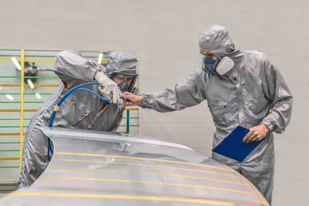 Empleado del taller de pintura de la fábrica de automóviles realiza capacitación sobre pintura de partes del cuerpo