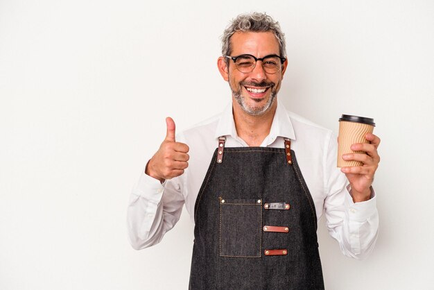 Empleado de una tienda de mediana edad sosteniendo un café para llevar aislado de fondo blanco sonriendo y levantando el pulgar