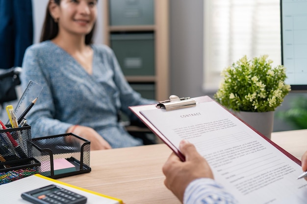 El empleador del hombre se sienta en el escritorio y tiene en las manos un contrato de trabajo para una mujer con discapacidad