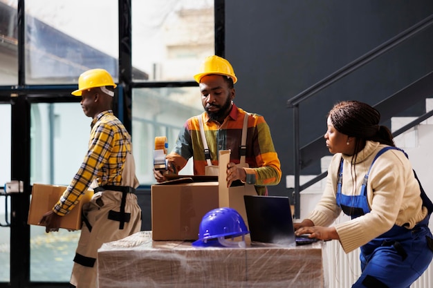 Empleados de almacén revisando la lista de pedidos en portátiles y paquetes de embalaje. Equipo de trabajadores de almacenes minoristas afroamericanos que preparan la mercancía para su envío en la sala de almacenamiento