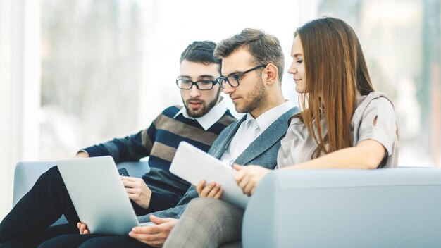 Empleados con una computadora portátil sentados en el vestíbulo de la oficina