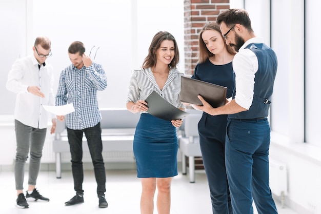 Empleados discutiendo documentos comerciales en el vestíbulo de la oficina