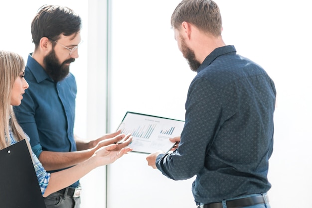 Empleados discutiendo documentos de pie en la oficina.