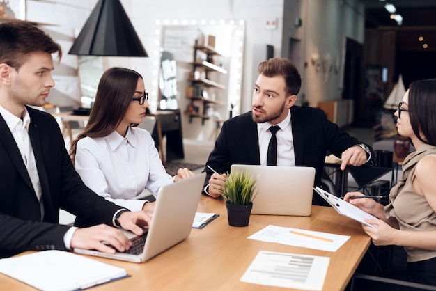 Los empleados de la empresa celebran una reunión en la mesa.