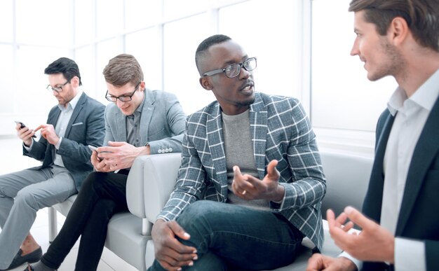 Los empleados de la empresa hablan sentados en el vestíbulo de la oficina.