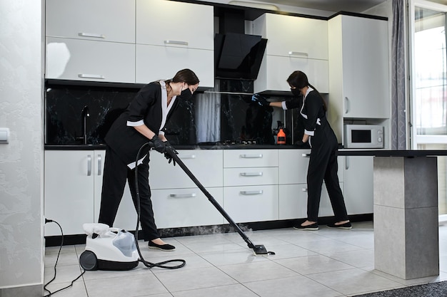 Foto empleados de la empresa de servicios de limpieza que retiran la cocina de limpieza con equipo profesional de limpieza a vapor