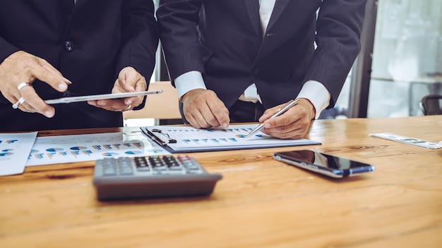 Empleados de la empresa usando tableta con gráfico de negocios.