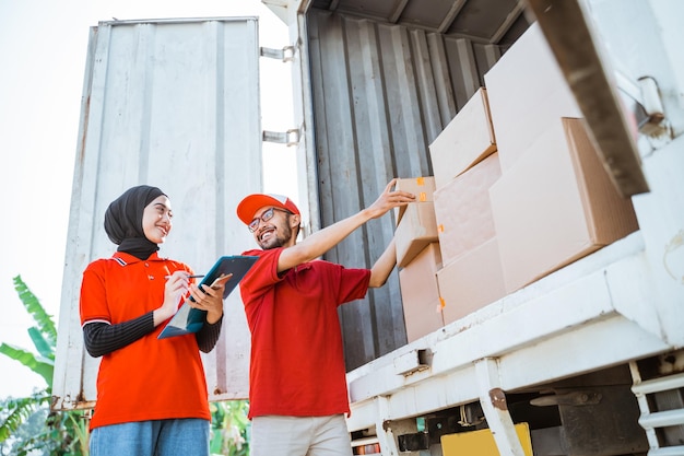 Empleados masculinos y femeninos manejan cajas empacadas en camiones contenedores