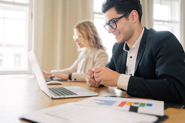 Empleados de oficina juntos alrededor de una computadora portátil Un hombre y una mujer en trajes de negocios intercambian ideas sobre