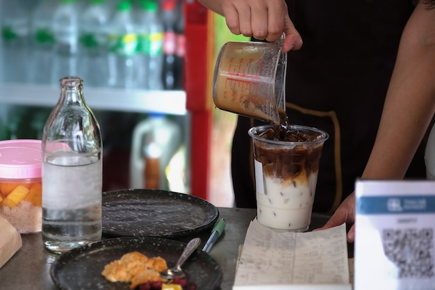 Los empleados ponen café en vasos para preparar café con leche para los clientes.