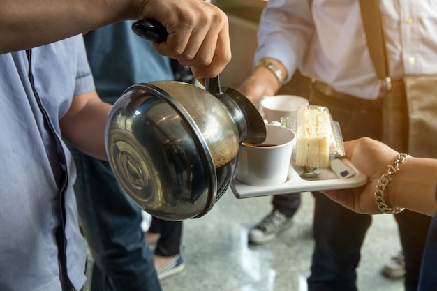 Los empleados reciben un descanso para tomar café entre la reunión y la merienda en un plato, concepto de café.