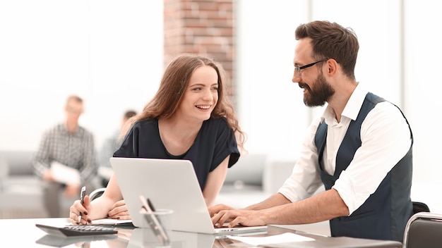 Los empleados sonrientes de la empresa discuten algo sentado en el escritorio los días laborables de la oficina.