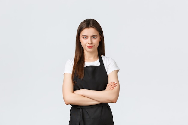 Empleados de la tienda de abarrotes, concepto de pequeñas empresas y cafeterías. Barista escéptico y decepcionado que parece preocupado, con los brazos cruzados en el pecho y una sonrisa disgustada, de pie sobre un fondo blanco.