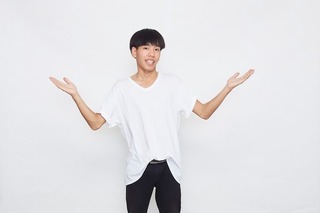 Empolgado surpreso com um jovem asiático fofo em uma camiseta branca casual, fazendo um gesto com a mão aberta na superfície cinza