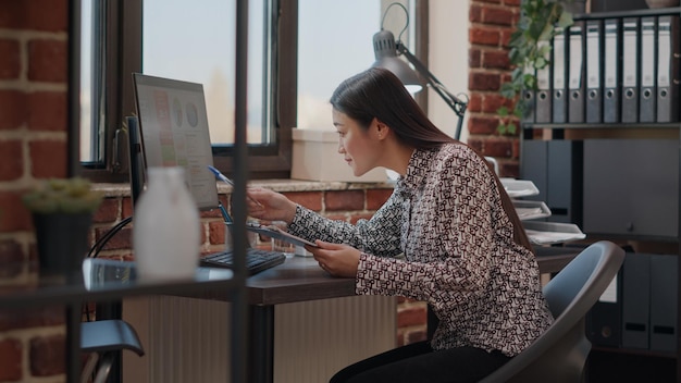 Empreendedor analisando papéis da área de transferência para planejar o projeto de negócios e a estratégia no escritório de inicialização. Pessoa que trabalha com documentos e computador para projetar o desenvolvimento de dados financeiros.