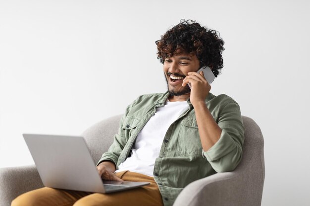 Foto empreendedor de cara indiano bonito positivo trabalhando on-line conversando por telefone