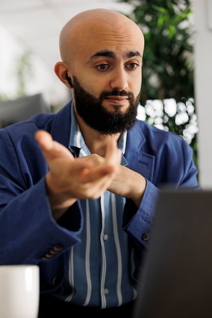 Empreendedor discutindo estratégia de inicialização com parceiro de negócios em videochamada no laptop enquanto trabalhava no escritório corporativo. Executivo falando sobre gerenciamento de projetos em reunião virtual com investidor