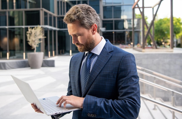 Empreendedor sério em traje de negócios usando pc fora do escritório freelancer