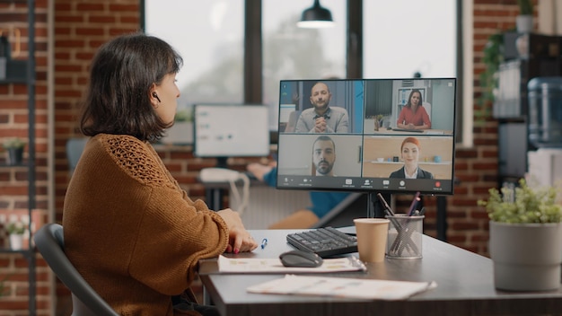 Empreendedor usando videochamada no computador para conversar com colegas sobre estratégia de marketing. Empregado participando de reunião de negócios com colegas de trabalho, falando sobre apresentação e projeto