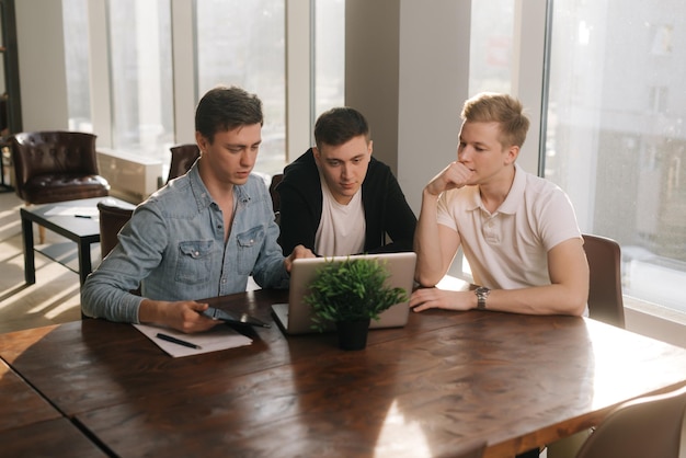 Empreendedores de pequenas empresas falando de estratégia à mesa com laptop em um escritório de inicialização moderno. Conceito de jovens empresários de trabalho em equipe.