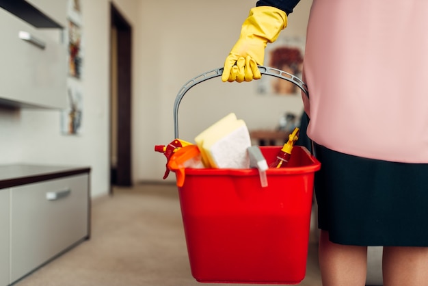 Empregada doméstica com as mãos em luvas contém equipamentos de limpeza, corredor do hotel. Limpeza profissional, faxineira