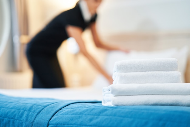 empregada fazendo cama em quarto de hotel