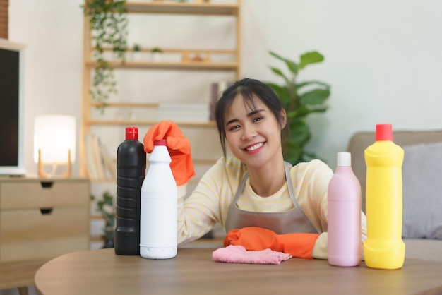 Empregada usando luvas e sentada no chão com garrafas de limpeza e pano para limpeza em casa