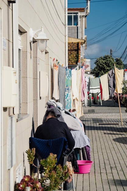 Empregadas velhas sentadas na porta da casa se escondendo de secar roupas e roupas ao sol