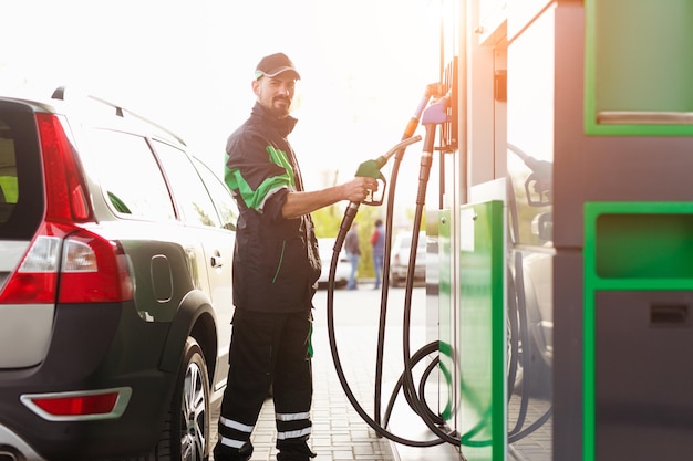 Empregado barbudo perto da bomba de gasolina