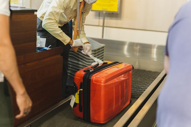Foto empregado coloca etiqueta na bagagem de passageiros no aeroporto