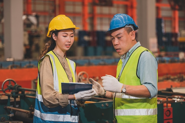 Empregado da equipe asiática que trabalha na fábricaGrupo de engenheiros da Ásia é controle de fabricação na fábrica industrial