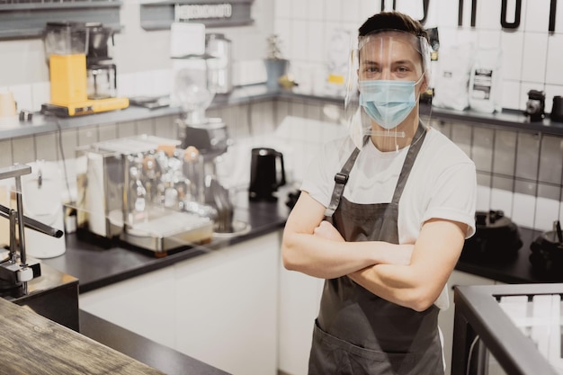 Empregado de café masculino usando máscaras contra infecção pandêmica por coronavírus em pé