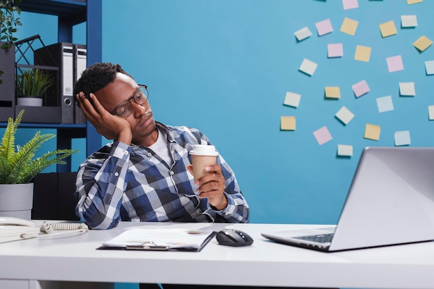 Foto empregado de escritório de agência cansado e exausto adormecendo na mesa por causa do trabalho de horas extras. líder de equipe estressado e cansado com síndrome de burnout sentado no espaço de trabalho do escritório moderno.