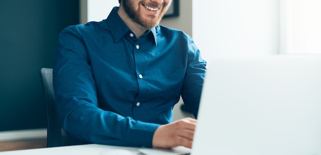 Foto empregado de escritório jovem feliz sem rosto trabalhando em um laptop