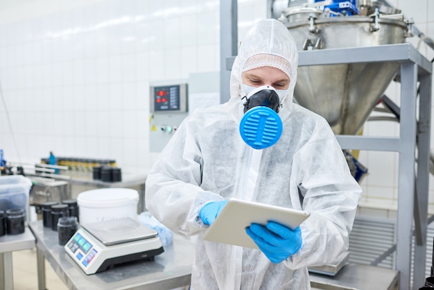 Empregado de fábrica em pé e usando tablet