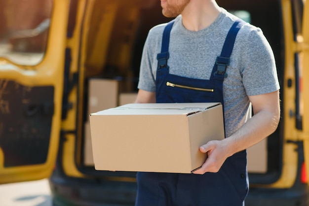 Empregado de serviço de entrega Retrato de homem trabalhando no serviço de entrega Retrato de correio com caixa Correio ao lado de minivan Carreira de serviço de entrega