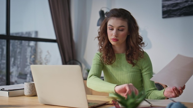 Empregado sério a ver papéis no escritório de perto Secretária a digitar laptop