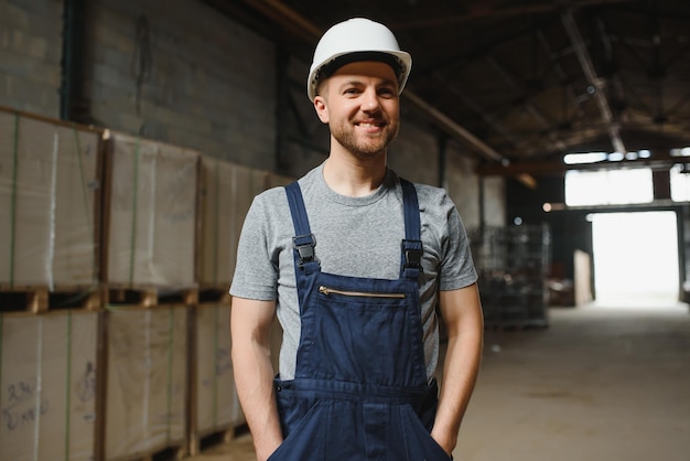 Empregado sorridente e feliz Trabalhador industrial dentro de casa na fábrica Jovem técnico com capacete branco