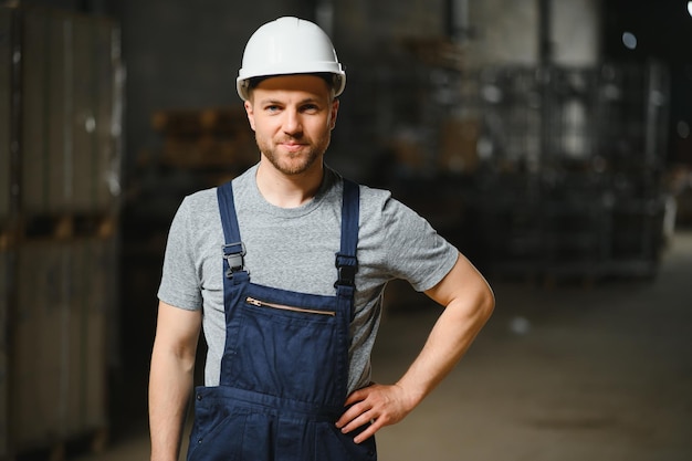 Empregado sorridente e feliz Trabalhador industrial dentro de casa na fábrica Jovem técnico com capacete branco