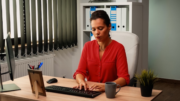 Empregado tomando café e lendo notícias sentado na frente do computador na sala do escritório. Empreendedor vindo para o trabalho, no espaço de trabalho de uma empresa profissional, digitando no teclado do pc, olhando para a área de trabalho