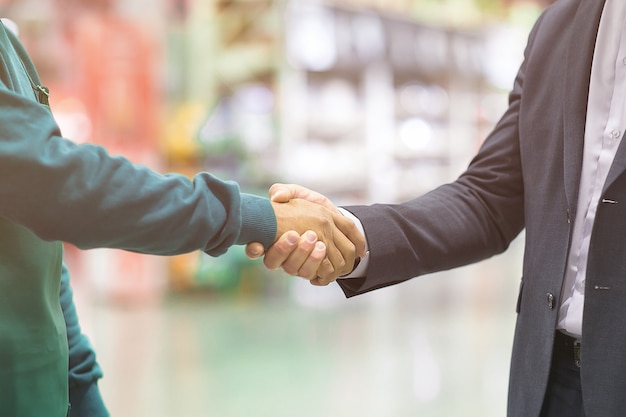 Empregador de aperto de mão de negócios e trabalhador no fundo desfocado do super mercado.