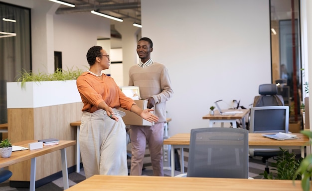 Empregador mostrando ao homem sua mesa em um novo emprego enquanto carrega a caixa de pertences