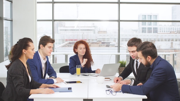 Empregados de escritório jovem de uma empresa de negócios, compartilhando uma mesa.