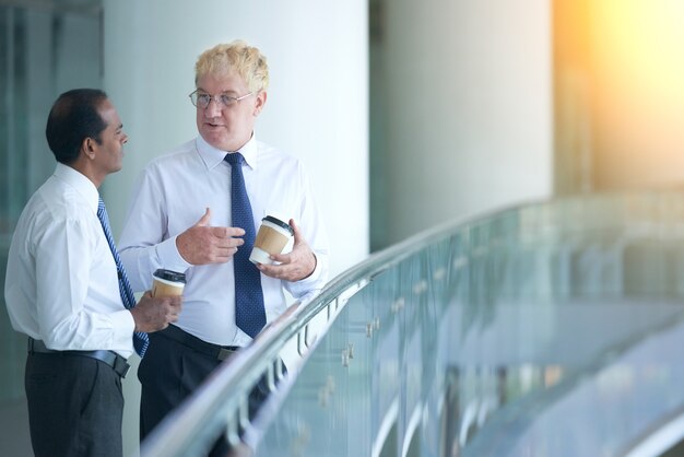 Emprendedor de experiencia de pie en el balcón del edificio de oficinas tomando café