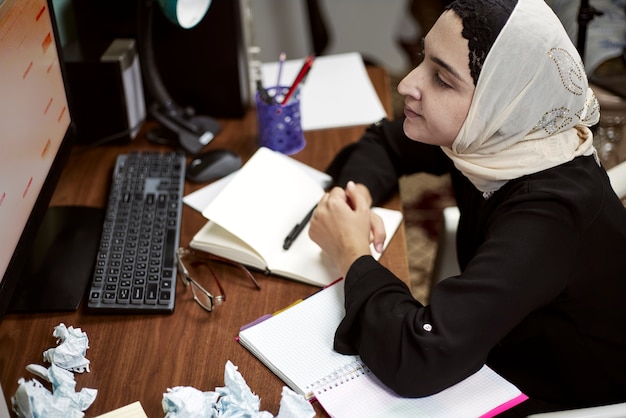 Foto emprendedora de oriente medio. ocupada empresaria árabe. mujer en ropa tradicional árabe hijab o abaya trabajando en pc