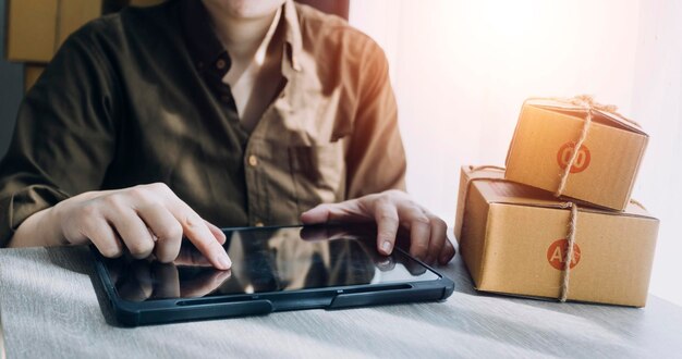 Emprendedores Pequeñas empresas PYME Hombres independientes trabajan en casa Utilizar teléfonos inteligentes y computadoras portátiles para la comprobación comercial en línea marketing cajas de embalaje vendedores PYME concepto de comercio electrónico equipo de ventas en línea